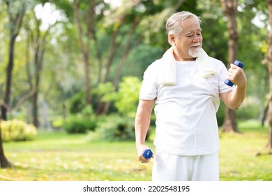 senior man exercising and lifting dumbbells in the park - Shutterstock ID 2202548195