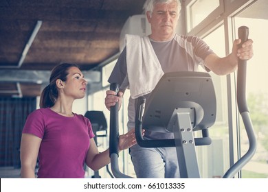 Senior man exercising on stationary bikes in fitness class. Man workout in gym. Senior with personal trainer. - Powered by Shutterstock