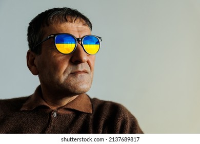 senior man with eyeglasses with the flag of Ukraine portrait. Grandfather, Portrait aged, elderly, loneliness, senior with lot of wrinkles on face. Close-up of a pensive old man at home - Powered by Shutterstock