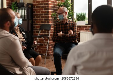 Senior Man With Face Mask Talking To People In Circle At Aa Meeting, To Cure Alcohol Addiction At Support Group Therapy. Person Having Discussion With Psychologist About Problems.