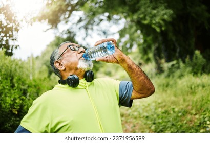 Senior man, fitness and drinking water in nature for hydration or natural sustainability after workout. Mature male person with mineral drink from exercise, training or cardio in recovery or break - Powered by Shutterstock