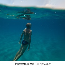 Senior Man Floating Underwater On The Blue Ocean -health And Activity Concept.