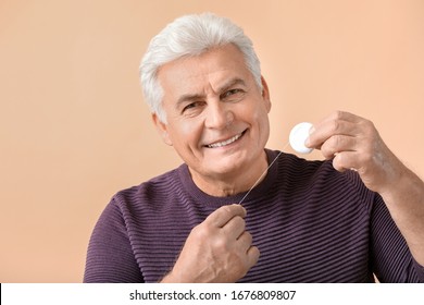 Senior Man Flossing Teeth On Color Background