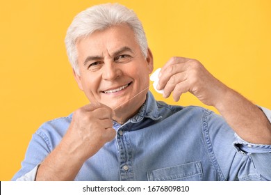 Senior Man Flossing Teeth On Color Background