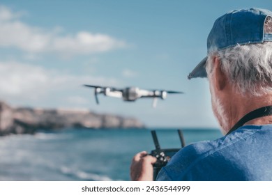 Senior man flying with drone at sunset using digital tablet remote control. Aerial photographs. Sea on background, horizon over water - Powered by Shutterstock