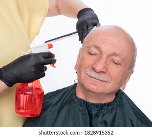 Senior Man Getting A Haircut Over White Background. Woman Wetting  Hair Before Cutting 