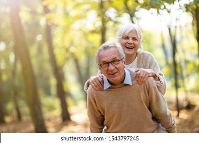 Senior Man Giving His Wife A Piggyback Outdoors

