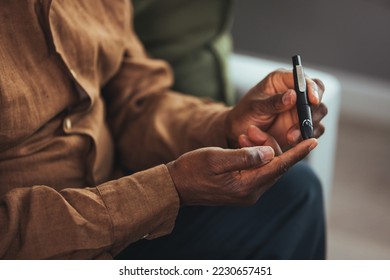 Senior man with glucometer checking blood sugar level at home. Elderly man testing for high blood sugar. Man holding device for measuring blood sugar. medicine, age, diabetes