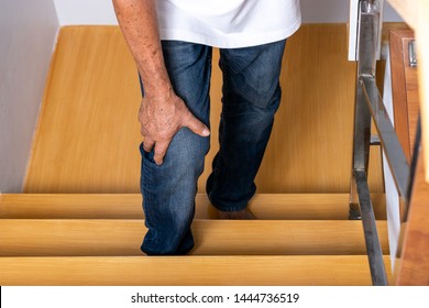 Senior Man Going Up The Stairs At Home And Touching His Knee By The Pain Of Arthritis. Health Care And Medical Concept. World Senior Citizen Day.