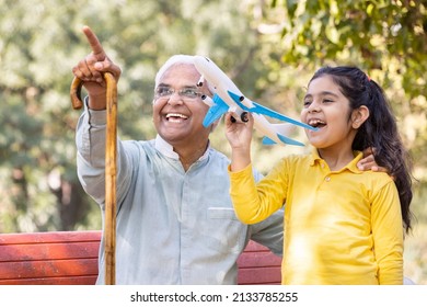 Senior Man With Granddaughter Having Fun Flying Toy Airplane At Park
