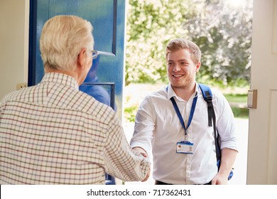 Senior man greeting male care worker making home visit