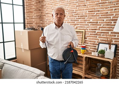 Senior Man With Grey Hair Holding Extension Plug Smiling Looking To The Side And Staring Away Thinking. 