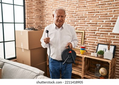 Senior Man With Grey Hair Holding Extension Plug Clueless And Confused Expression. Doubt Concept. 