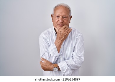 Senior Man With Grey Hair Standing Over Isolated Background Looking Confident At The Camera Smiling With Crossed Arms And Hand Raised On Chin. Thinking Positive. 