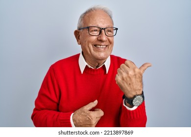 Senior Man With Grey Hair Standing Over Isolated Background Smiling With Happy Face Looking And Pointing To The Side With Thumb Up. 