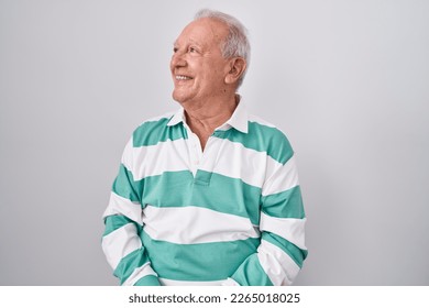 Senior man with grey hair standing over white background looking away to side with smile on face, natural expression. laughing confident.  - Powered by Shutterstock