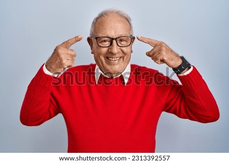 Senior man with grey hair standing over isolated background smiling pointing to head with both hands finger, great idea or thought, good memory 