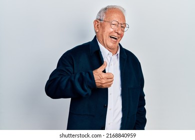 Senior man with grey hair wearing casual style and glasses doing happy thumbs up gesture with hand. approving expression looking at the camera showing success. 