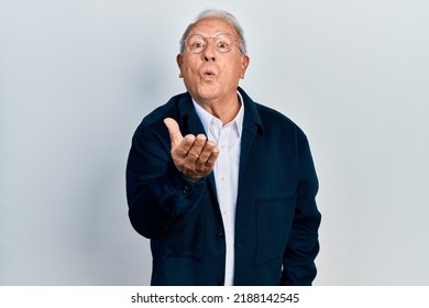 Senior Man With Grey Hair Wearing Casual Style And Glasses Looking At The Camera Blowing A Kiss With Hand On Air Being Lovely And Sexy. Love Expression. 