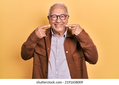 Senior man with grey hair wearing casual jacket and glasses smiling cheerful showing and pointing with fingers teeth and mouth. dental health concept.  - Powered by Shutterstock