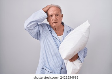 Senior man with grey hair wearing pijama hugging pillow confuse and wondering about question. uncertain with doubt, thinking with hand on head. pensive concept.  - Powered by Shutterstock