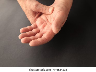 A Senior Man Grips His Sore Hand On A Black Background With Copy Space.