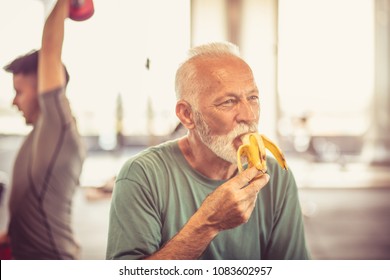 Senior Man At Gym Eating Banana.