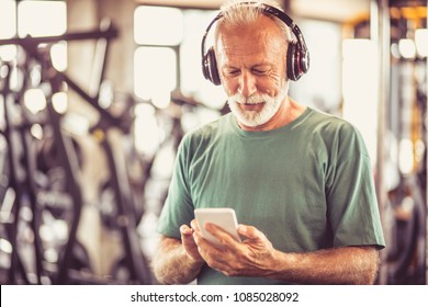Senior Man At Gym Listening Music.
