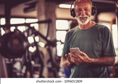 Senior Man At Gym Listening Music On Smart Phone.