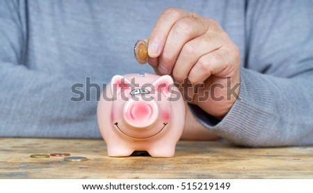 senior man hand putting money to piggy bank                                      