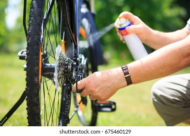 Senior Man Hands Spraying An Oil To Chain From The Wheel Bike, Doing Maintenance