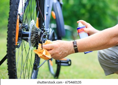 Senior Man Hands Spraying An Oil To Chain From The Wheel Bike, Doing Maintenance