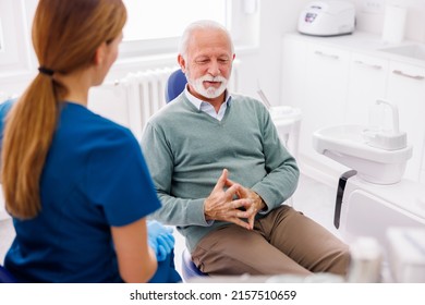 Senior Man Having Dentist Appointment Sitting At Dental Chair Consulting With Doctor At Dental Clinic