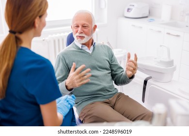 Senior man having dentist appointment sitting at dental chair consulting with doctor at dental clinic - Powered by Shutterstock