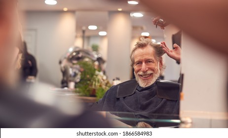 Senior Man Having Hair Cut By Female Stylist In Hairdressing Salon