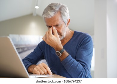 Senior Man Having A Headache While Working On Laptop Computer