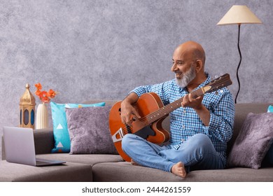 Senior man having online guitar lesson through laptop - Powered by Shutterstock