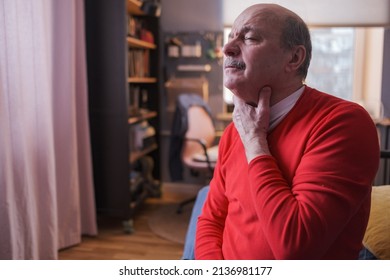 Senior man having sore throat and touching his neck at home