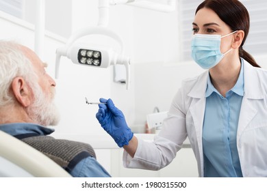 senior man having teeth examination by dentist in latex gloves with mirror in dental chair - Powered by Shutterstock