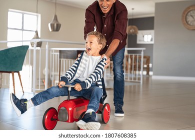 Senior man helping boy ride his toy car at home. Grandfather pushing kid car with little grandson inside to go faster. Excited boy and palyful elderly man playing together at home, copy space. - Powered by Shutterstock