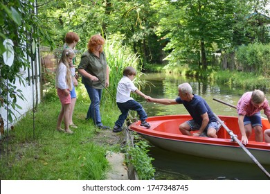 Senior man helping grandchild board rowing boat - Powered by Shutterstock