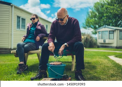 A Senior Man And His Adult Daughter Are Enjoying A Barbecue In The Trailer Park