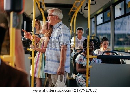 A senior man and his granddaughter are having a ride in the public transport