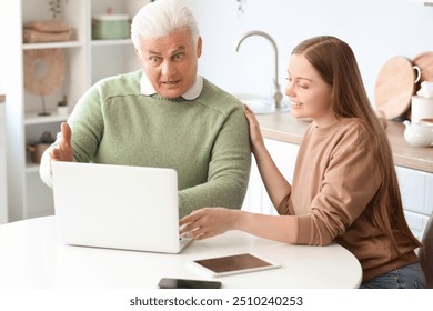 Senior man with his granddaughter using laptop in kitchen - Powered by Shutterstock