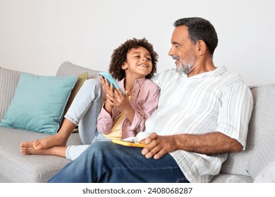 Senior man and his grandson boy engaged with mobile game on smartphone, sharing fun bonding moment in their living room, bridging generations through technology and gadgets - Powered by Shutterstock