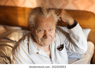 Senior Man In His Pajamas Sitting On A Bed