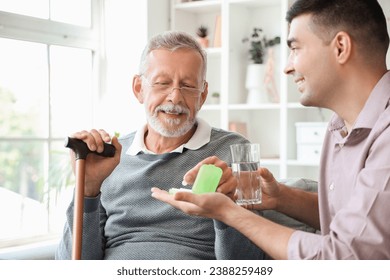 Senior man with his son taking pills at home - Powered by Shutterstock