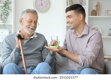 Senior man with his son taking pills at home - Powered by Shutterstock