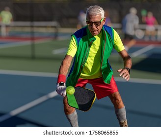 Senior Man Hitting A Pickleball With Paddle