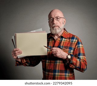 senior man is holding a blank sheet of paper and a pen, presentation or teaching concept - Powered by Shutterstock